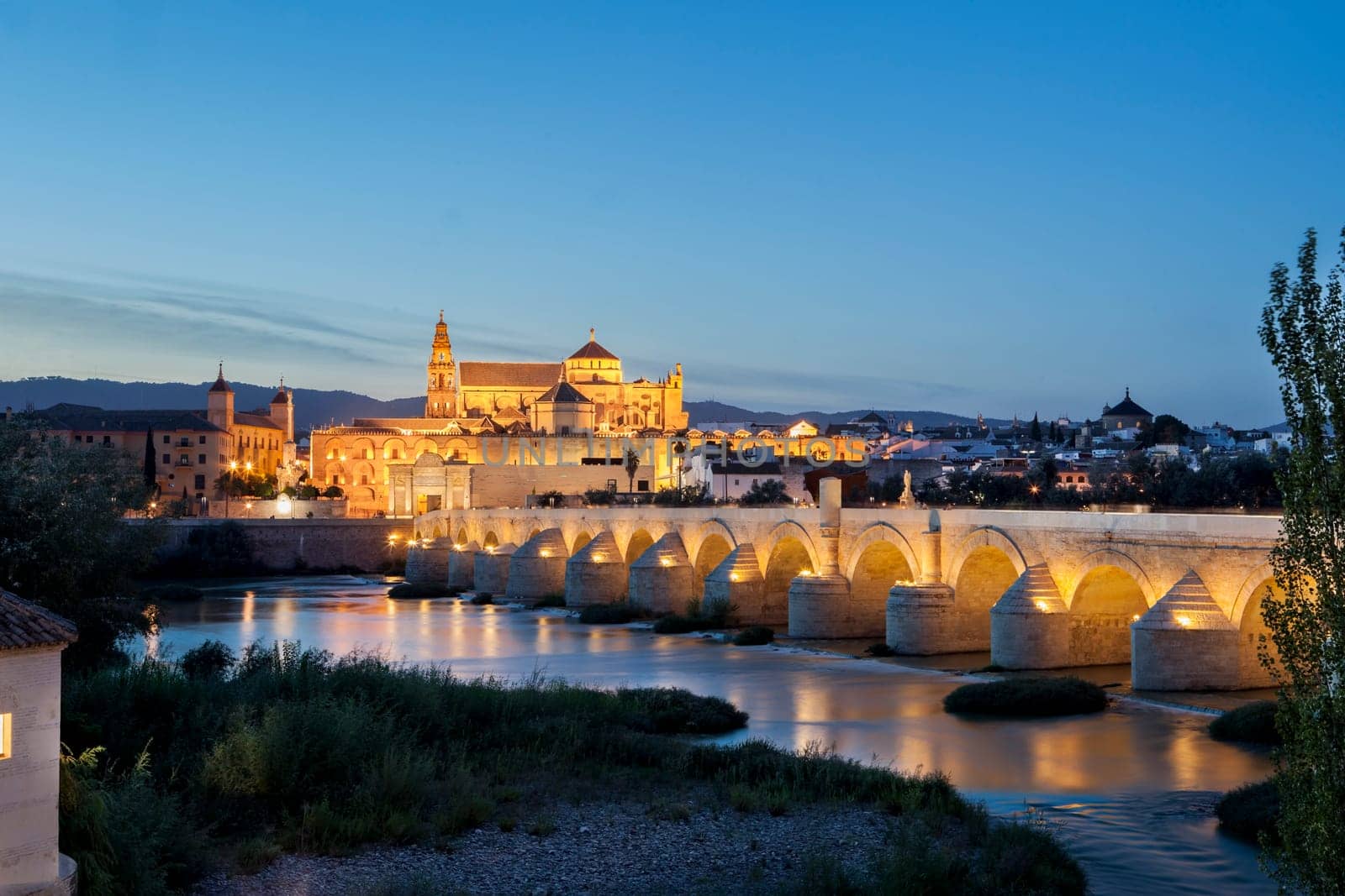 Saint Antonio Watermill on the Guadalquivir in Cordoba, Spain. Night scene with some couples sitting and the Mosque at bottom