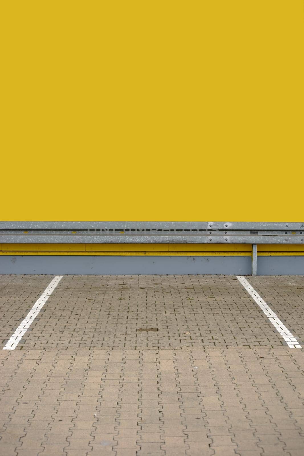 A single parking lot with markings and a guardrail at the end.