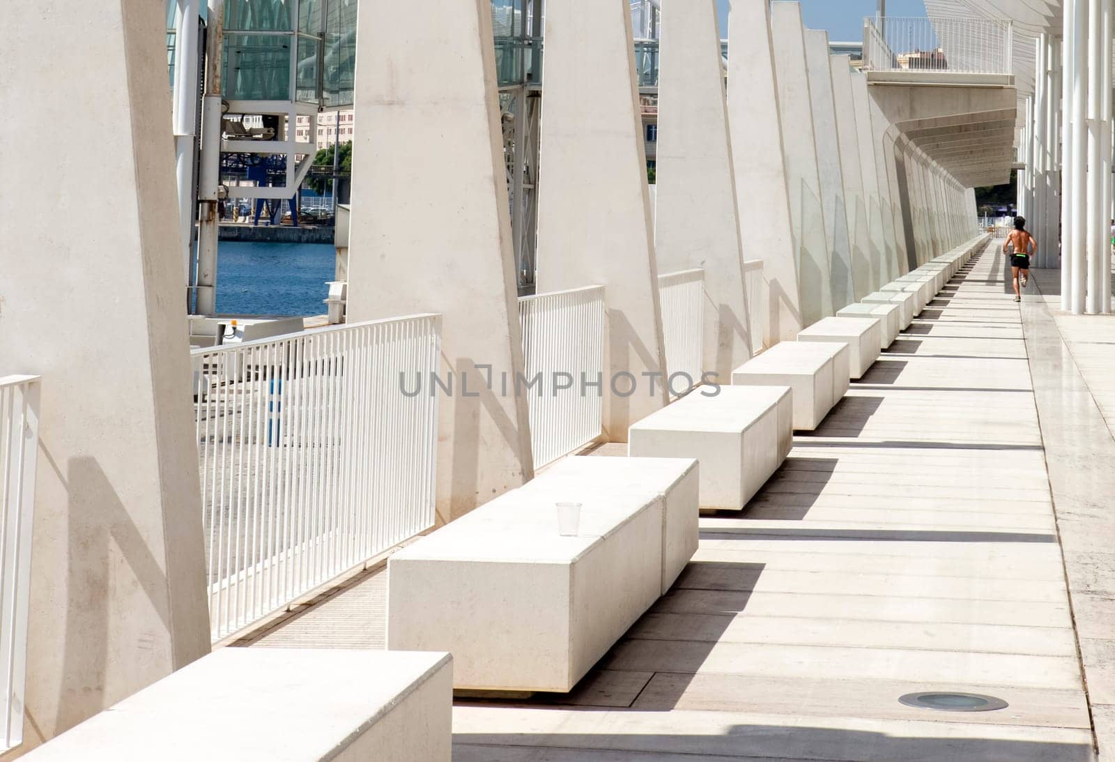 Sweaty  sportsman running under Malaga main boardwalk a sunny day with blue sky