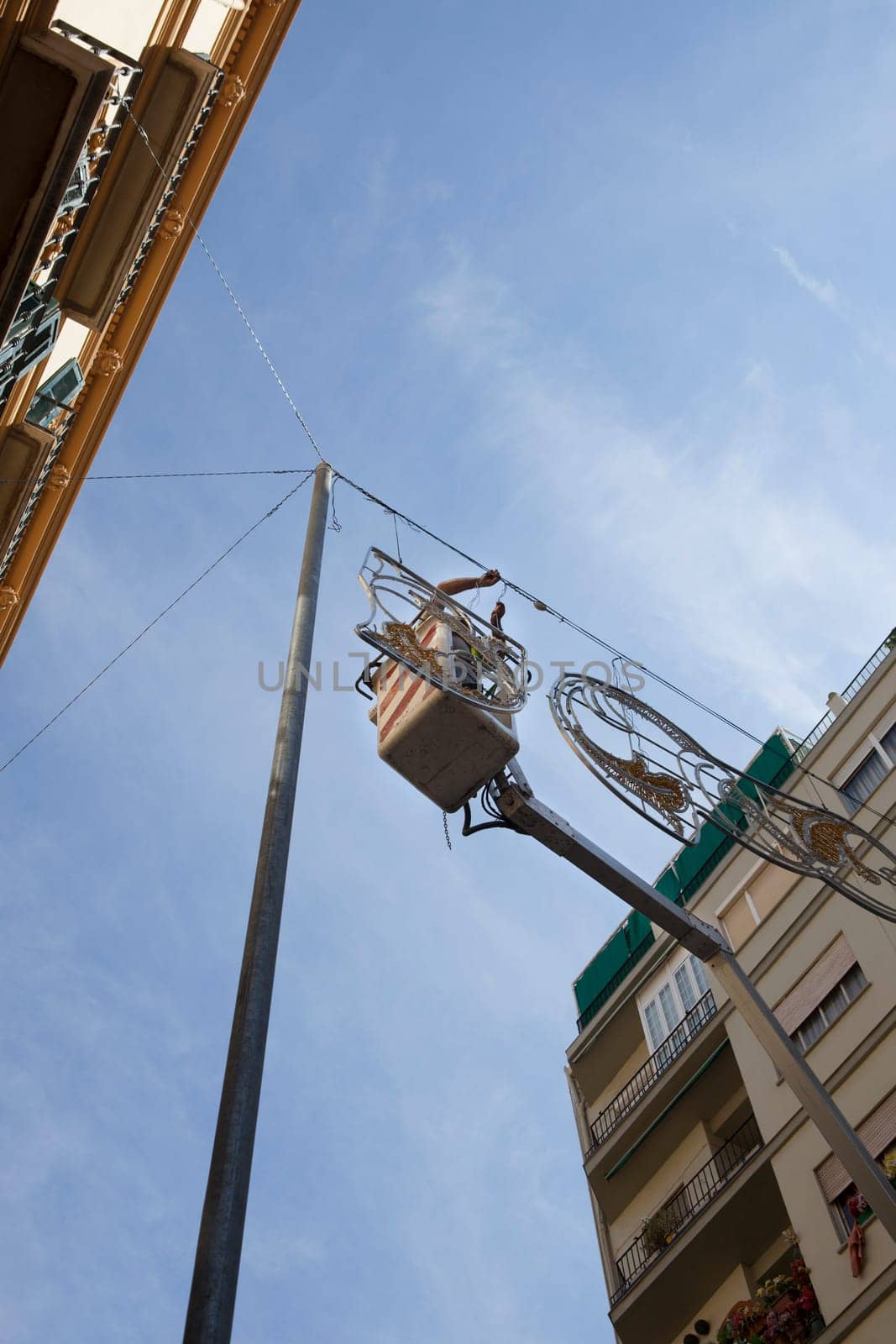 Electrician stays on cherry picker and repairs electric city decoration