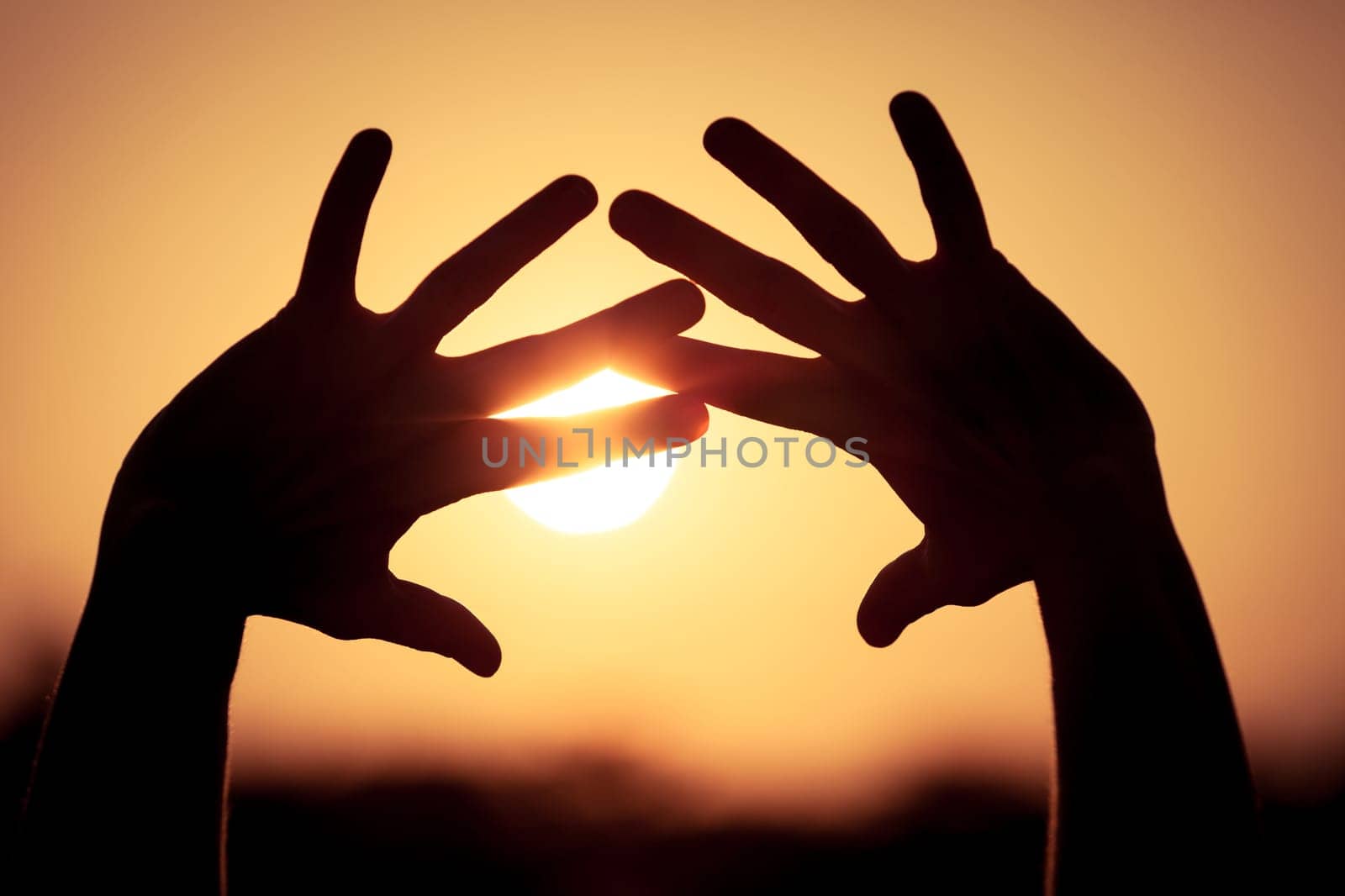 silhouette of female hands during sunset