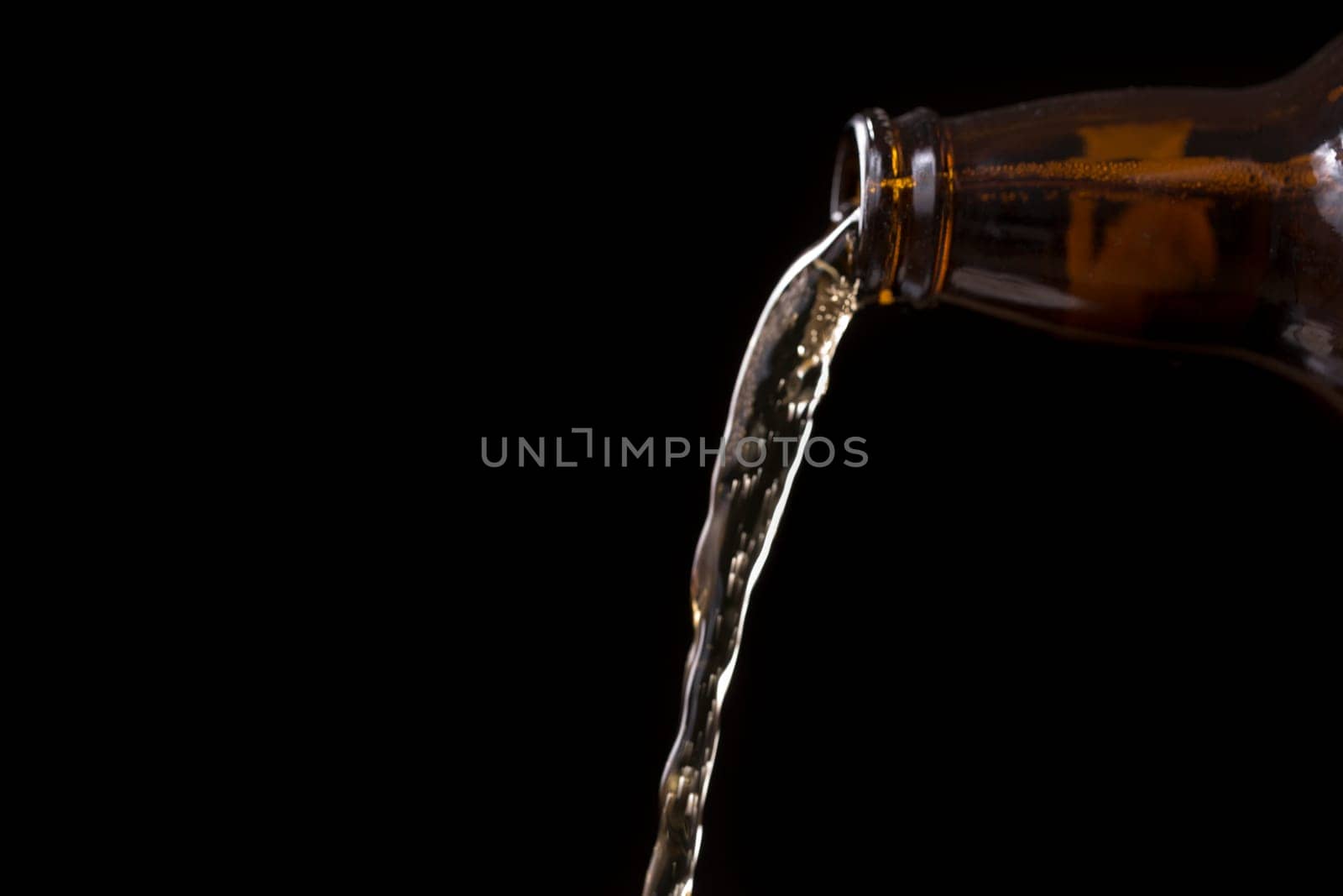 Beer Pouring From Bottle with black background.