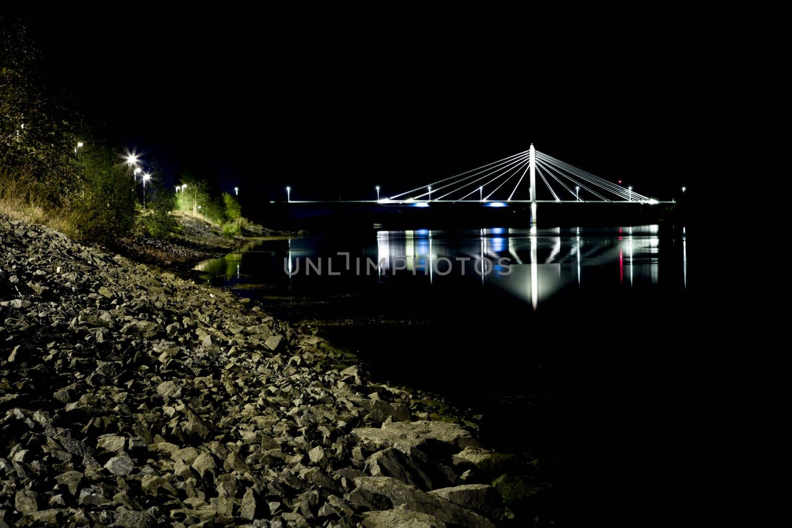 Cable Bridge in Umeå, Sweden at night with reflections in the water.