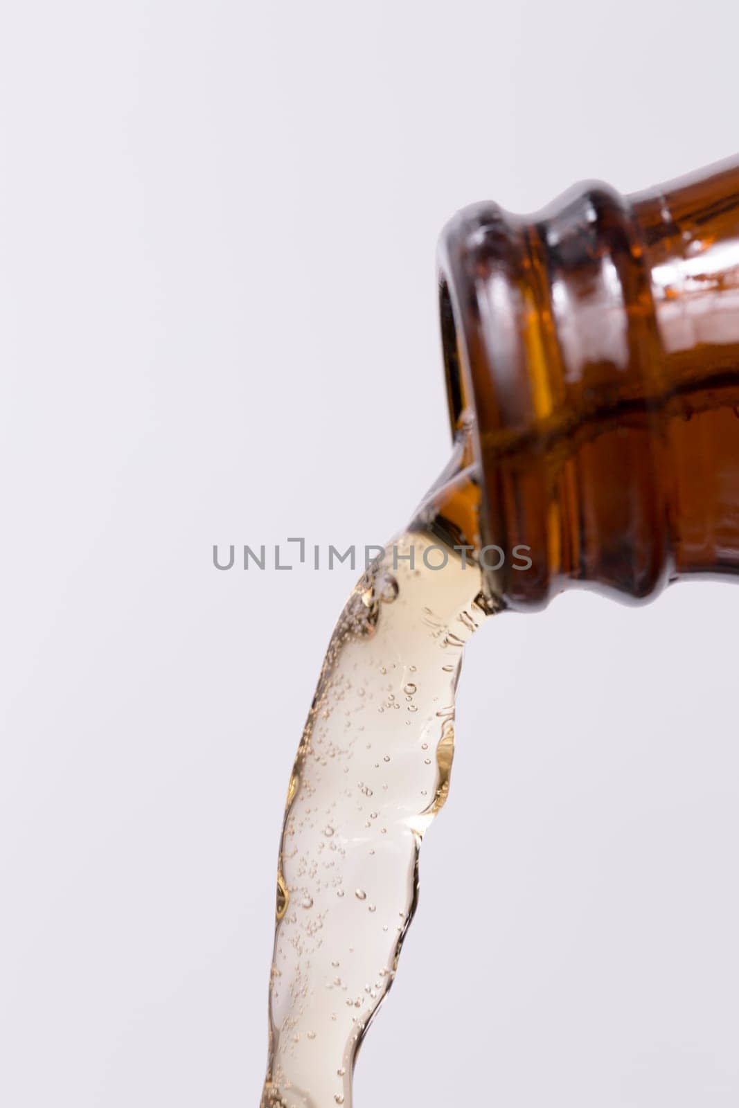 Beer Pouring out of Bottle with bubbles in the beer on white background.