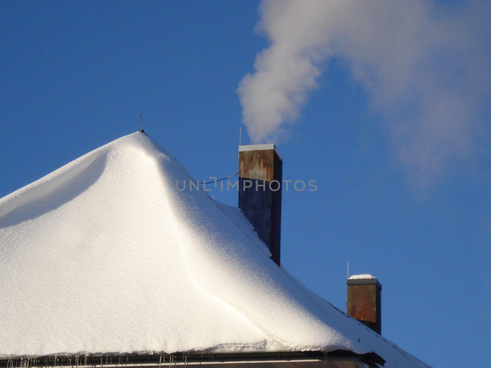 Smoking fireplace in a steel-blue sky - on an icy December day,12/12/12. The wind has shaped the snow