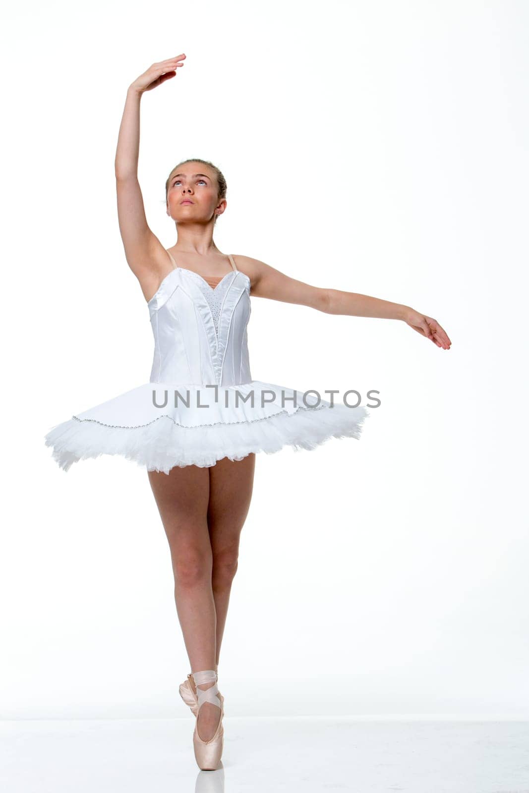 Young ballet dancer performing against a white background.