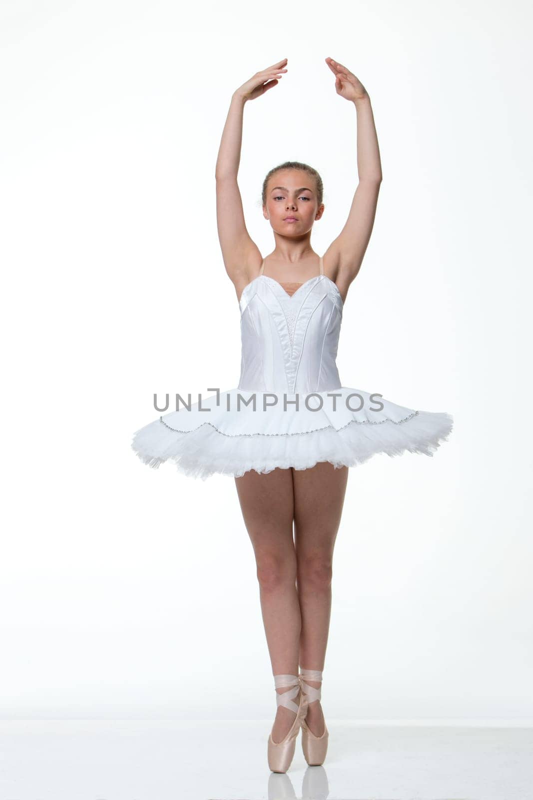 Young ballet dancer performing against a white background.