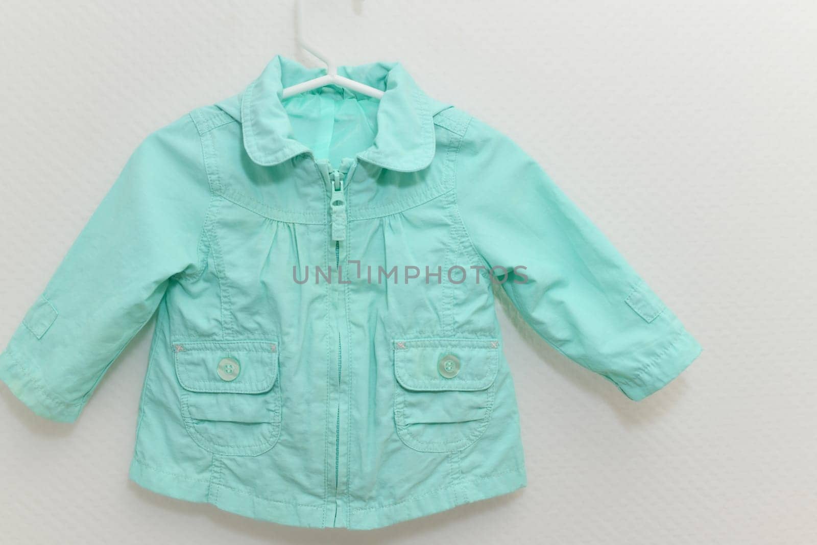 Menthol colored jacket for girl hanging on hanger on white background