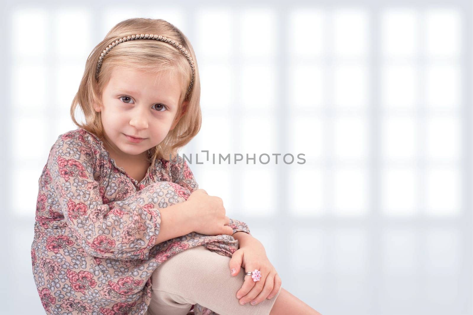 Cute little girl sitting in front of windows