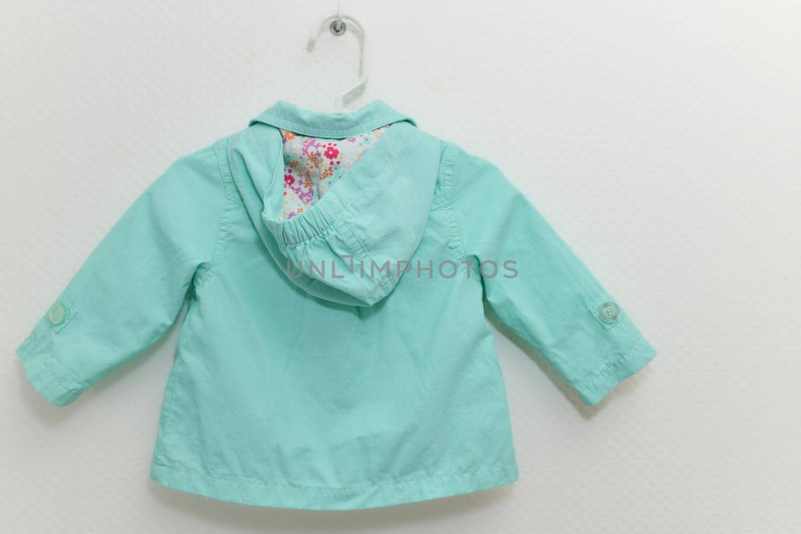 Menthol colored jacket for girl hanging on hanger on white background