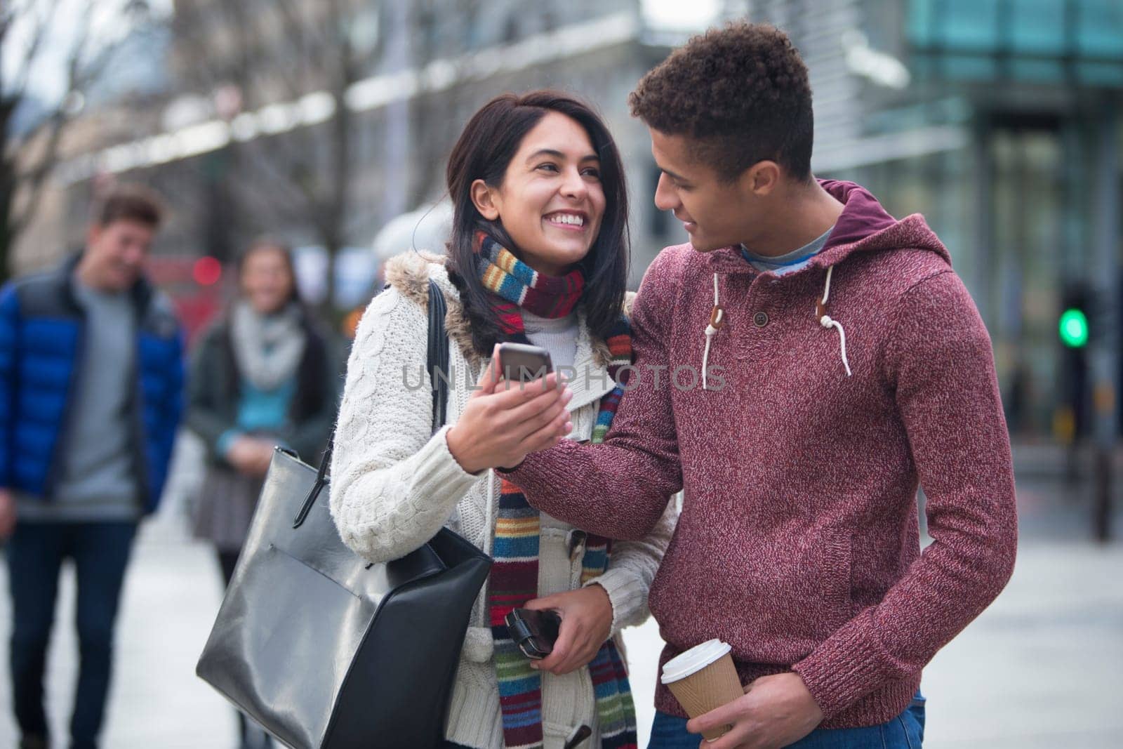 Young couple standing together in the city, looking at a smart phone