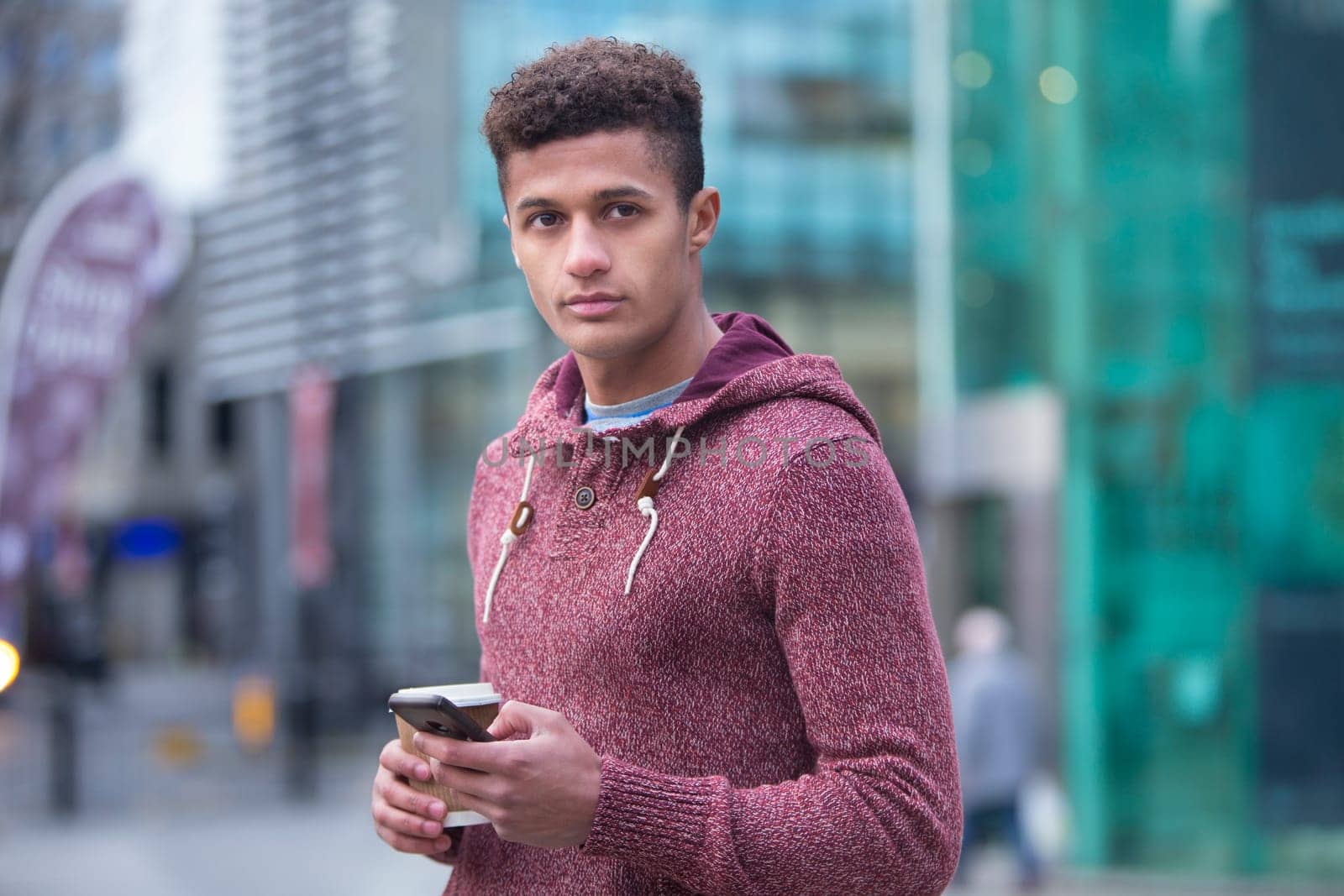Young, mixed-race man in the city with a smart phone