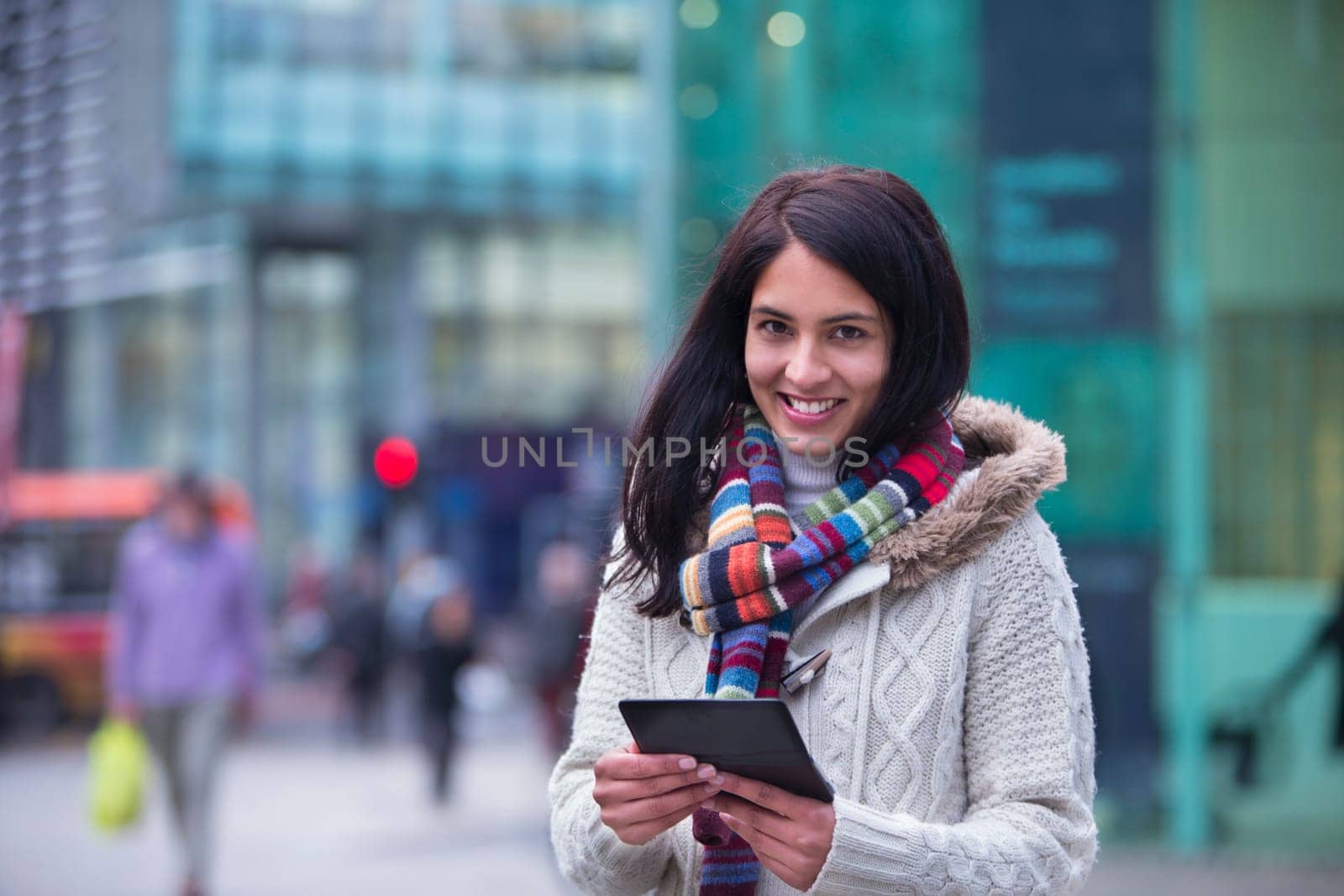 Young woman in the city with a smartphone. She is smiling at the camera.