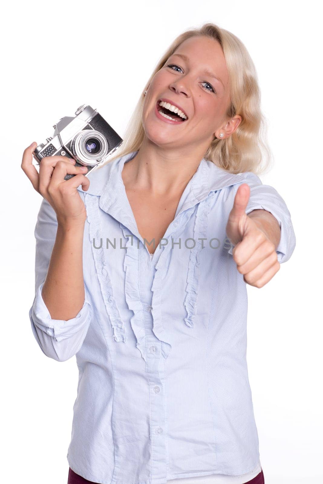Young woman holds an analog camera and shows up thumbs up