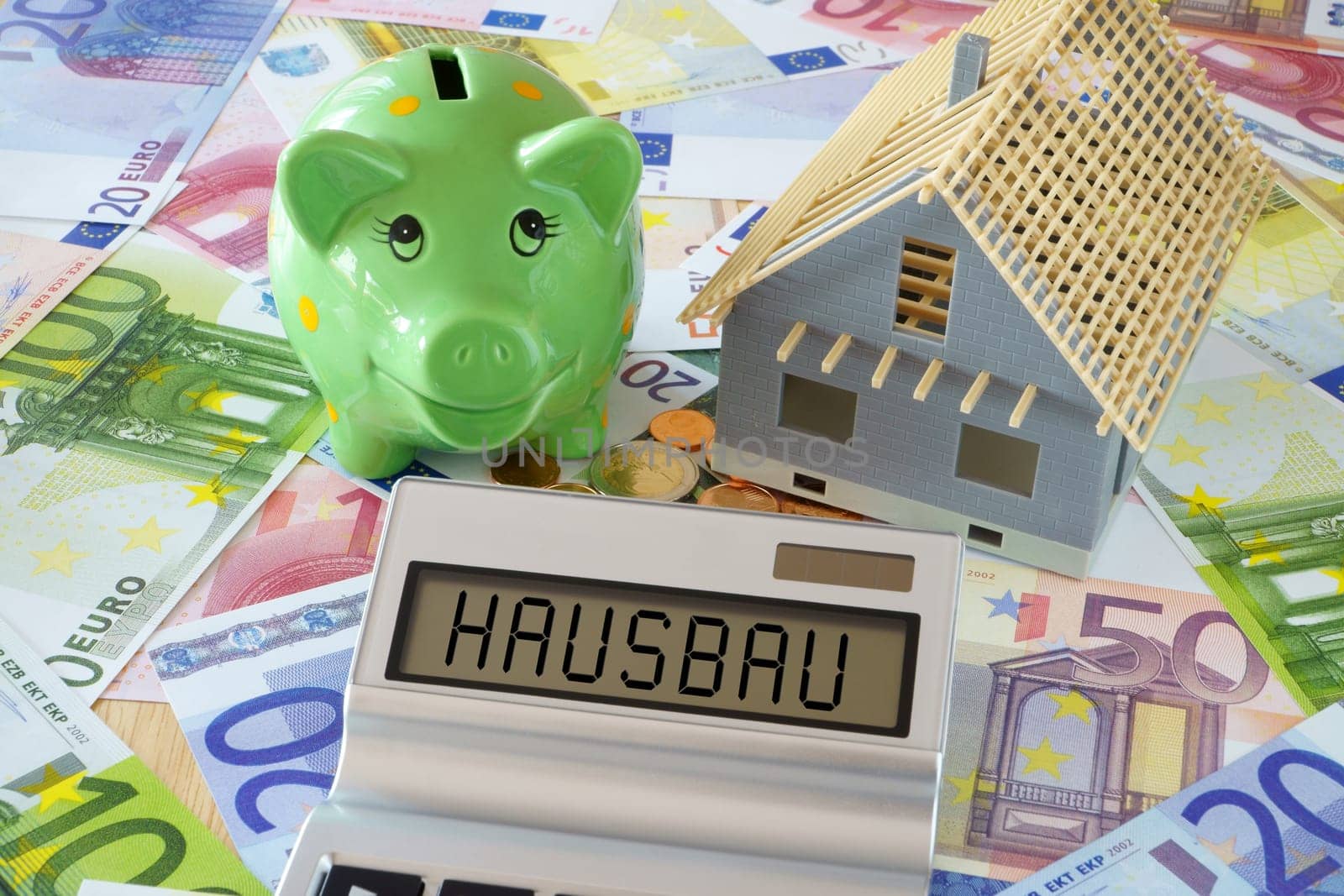 The word house building on display of calculator and piggy bank