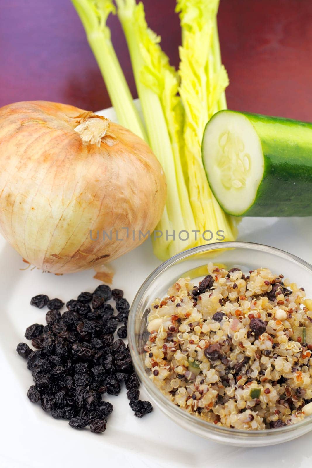 A small bowl of cooked three colors of quinoa.cooked with some of the raw ingredients shown next to it on a plate..