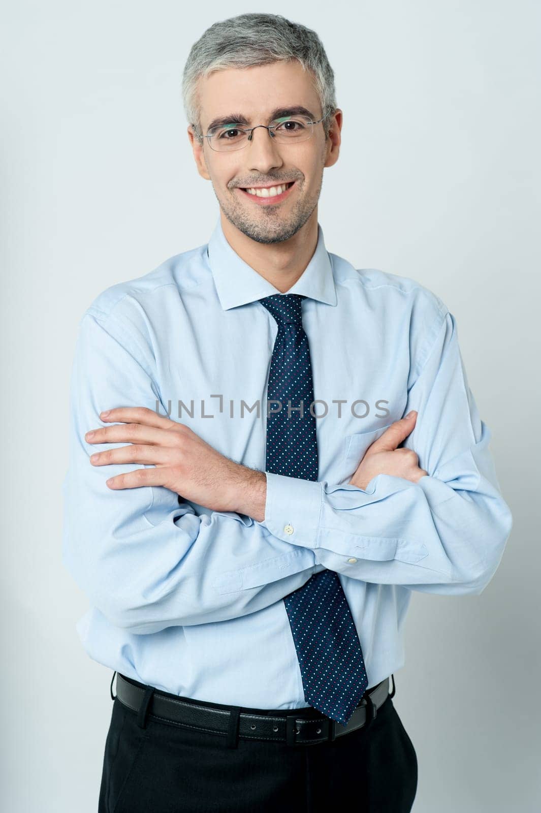 Handsome young employee standing with his arms crossed