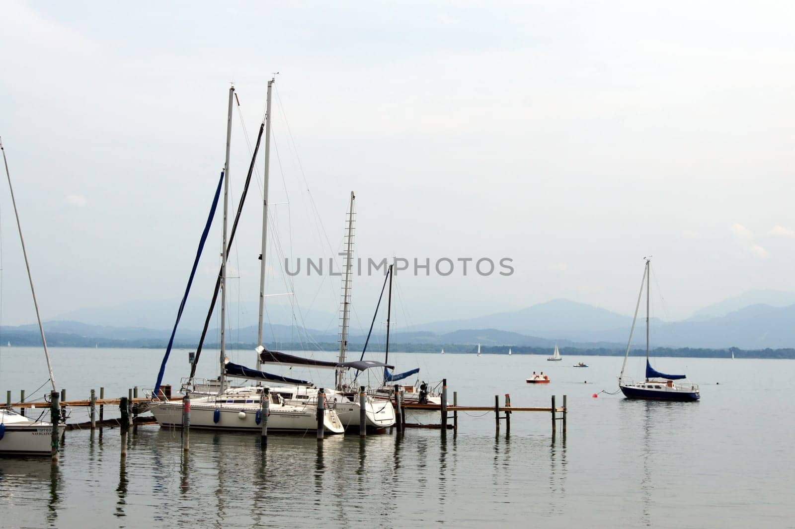 View of a pier with jetty and sailboats in Gstaad on Lake Chiemsee