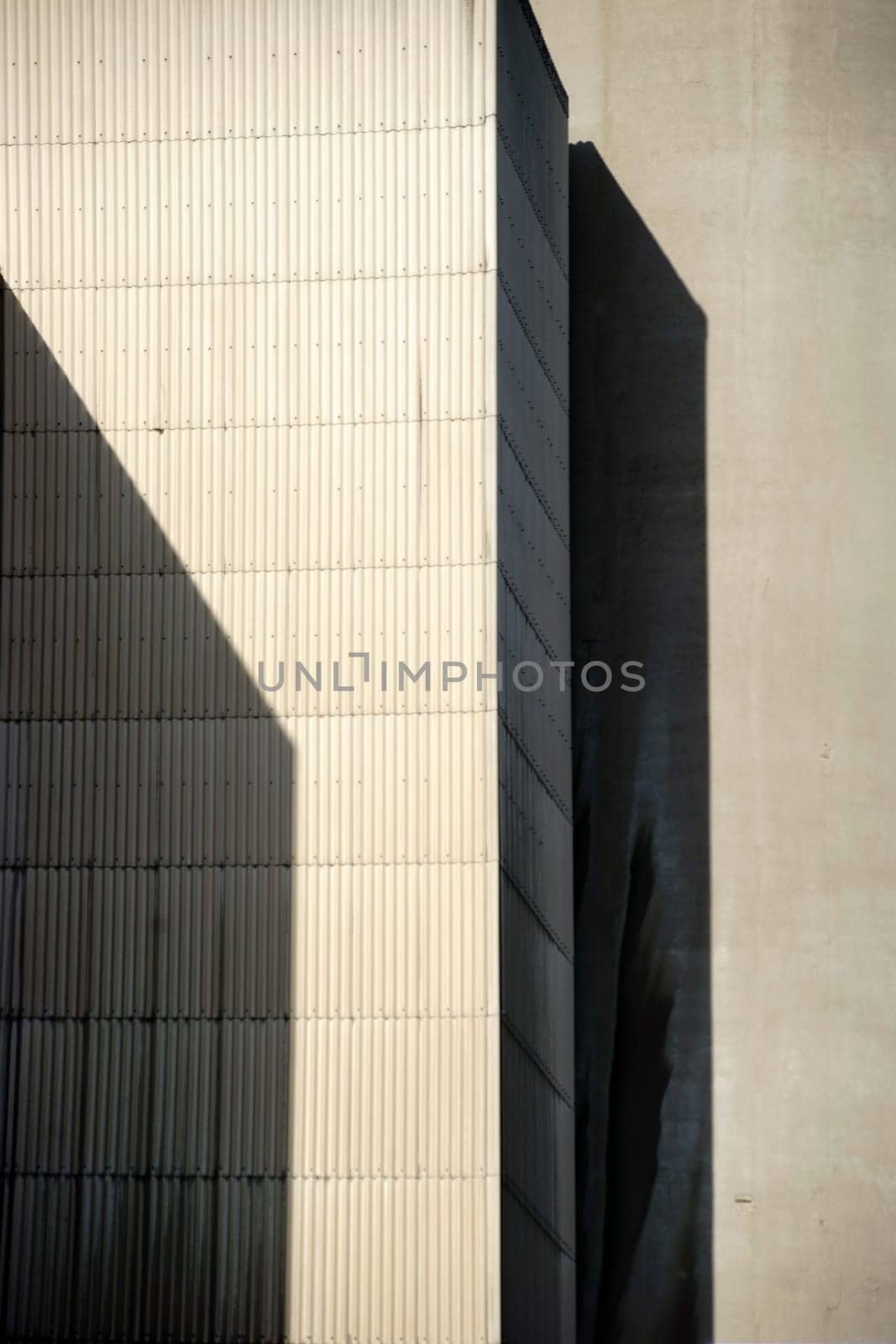 The corners and edges of an industrial building cast geometric shadows.