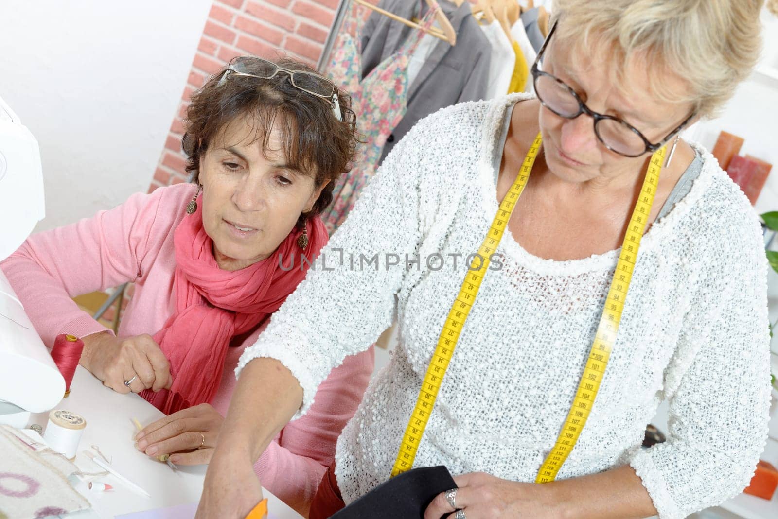 Two cheerful seamstresses working together in their fashion workshop