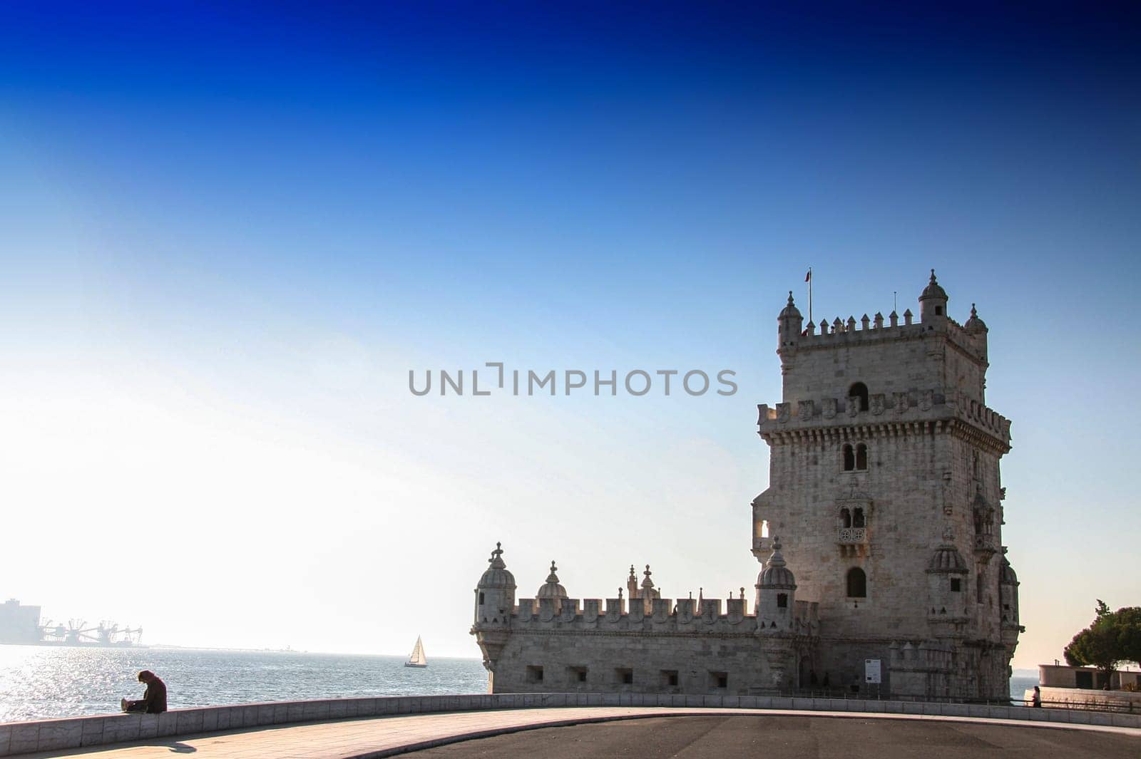 Unidentified woman reading beside the Belem Tower, a fortified tower located in the parish of Santa Maria de Belem in Lisbon, Portugal