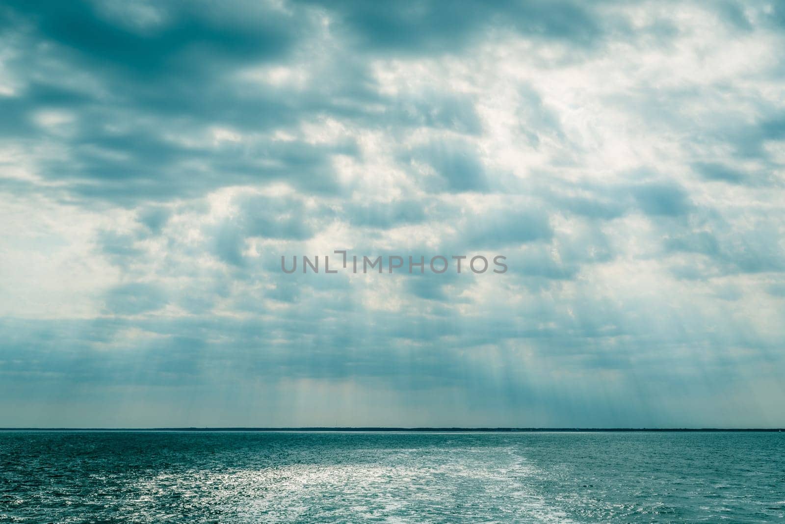 Clouds over the ocean with sunbeams in daylight