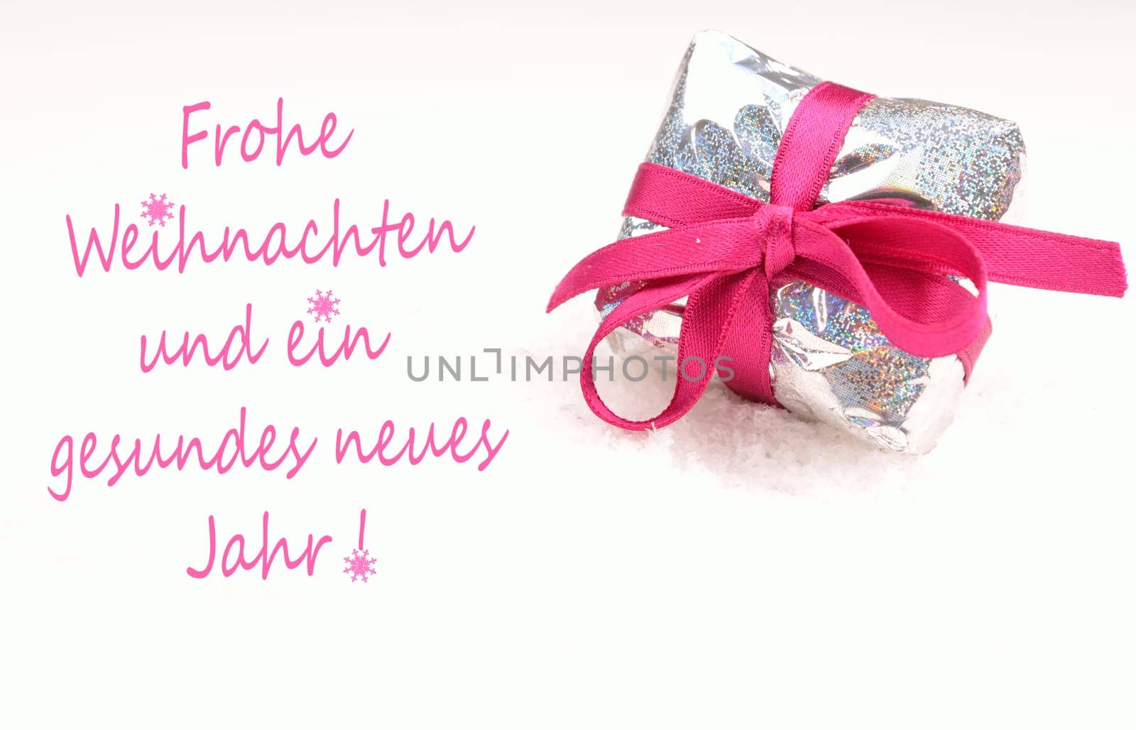 Christmas present in silver with a pink bow on a white snow background, German Merry Christmas background