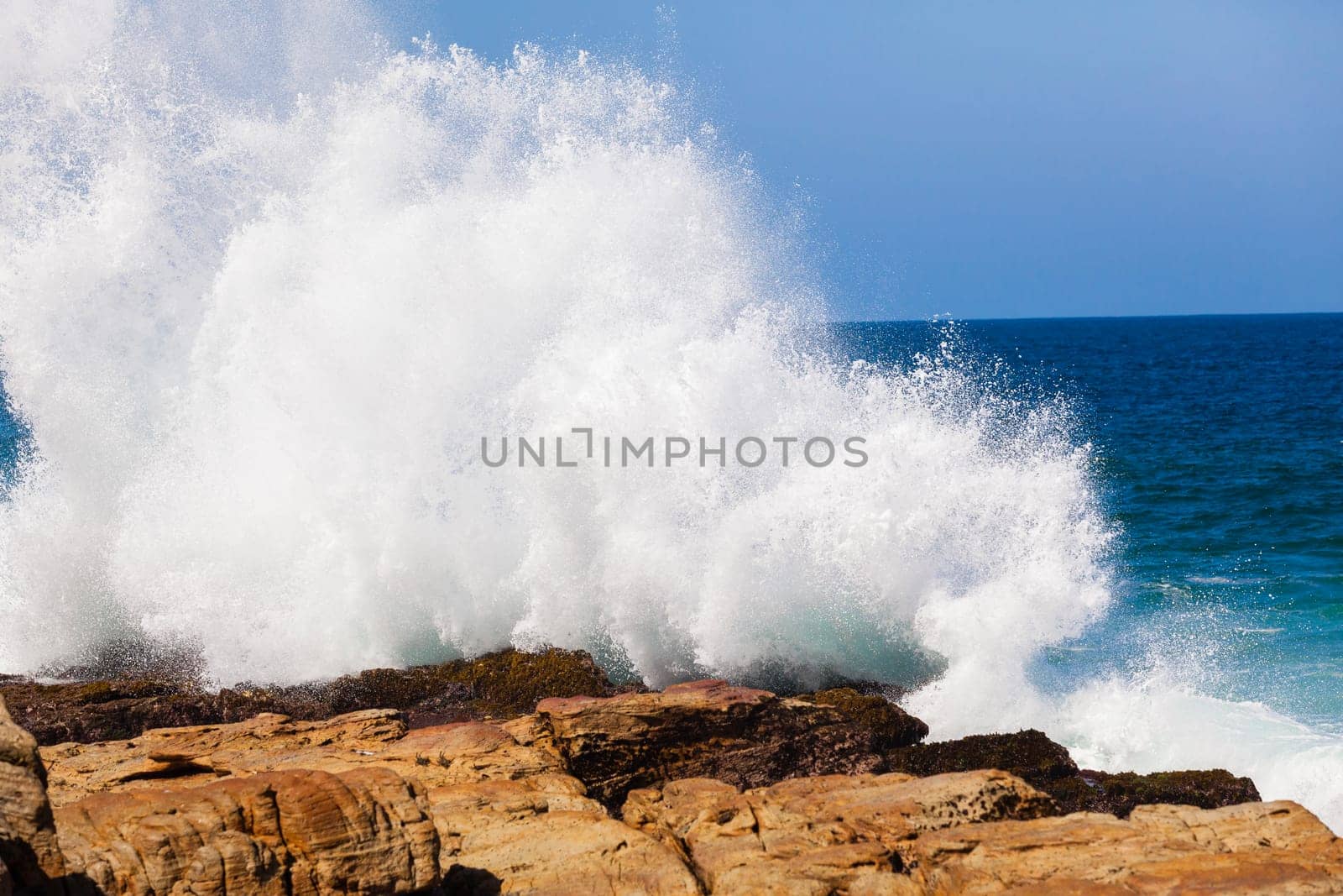 Ocean wave crashing rocky shoreline exploding white water power