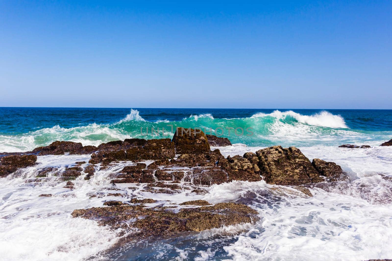 Ocean wave crashing rocky shoreline exploding white water power