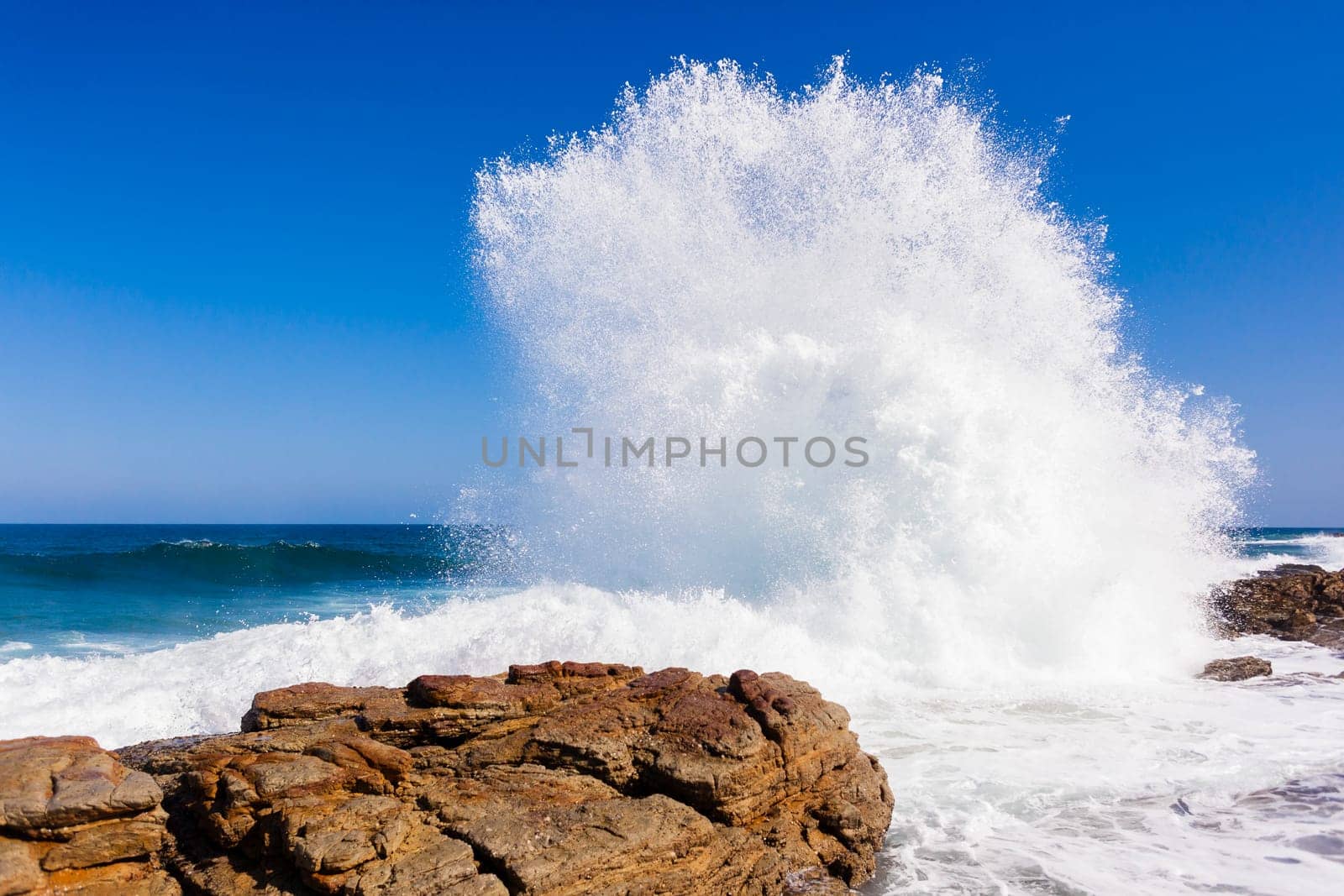 Ocean wave crashing rocky shoreline exploding white water power