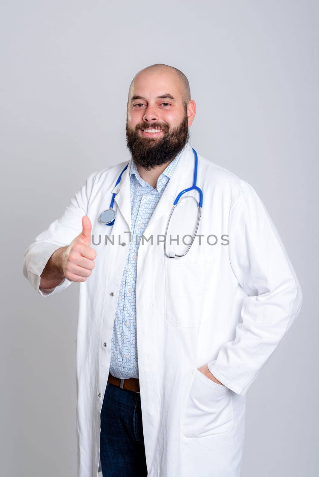 young bearded doctor in white coat and thumb up