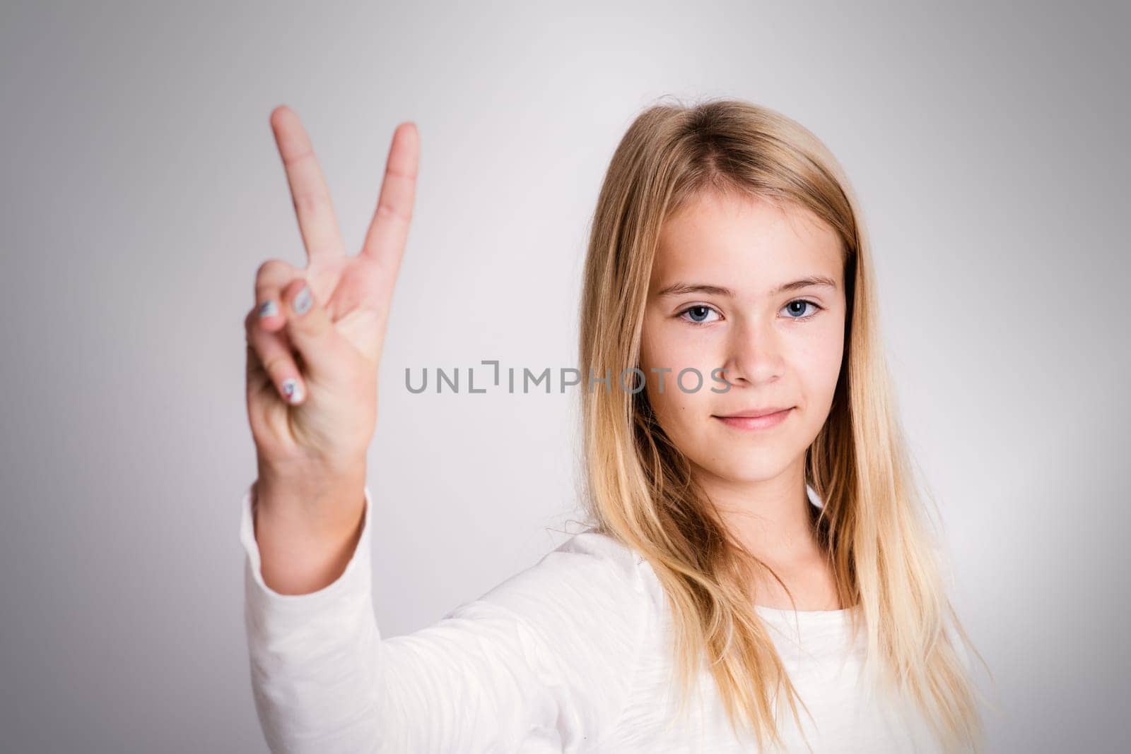 nice blond girl in front of gray background showing victory sign