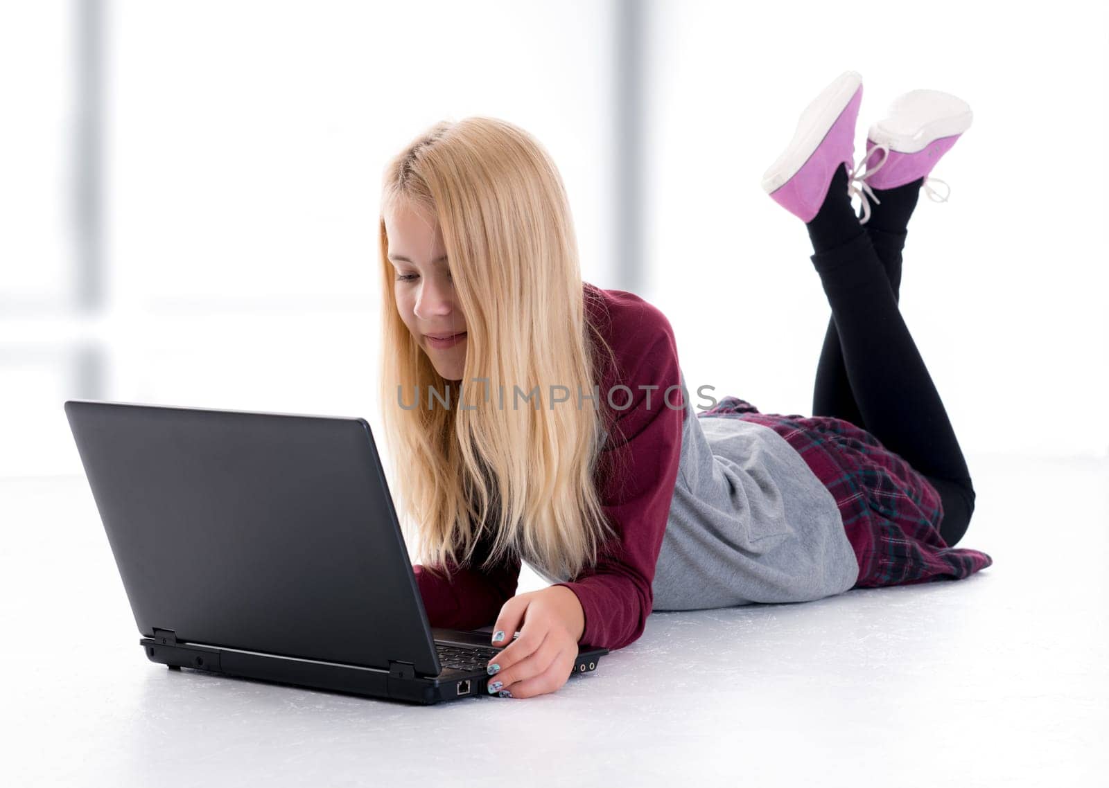 nice blond girl with laptop lying on the floor