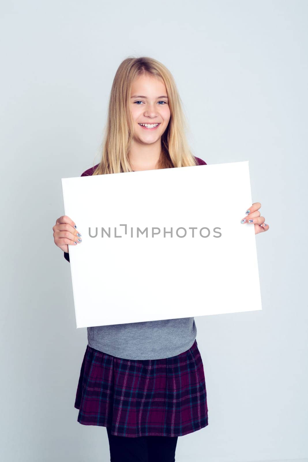 nice blond girl in front of gray background showing a white sign