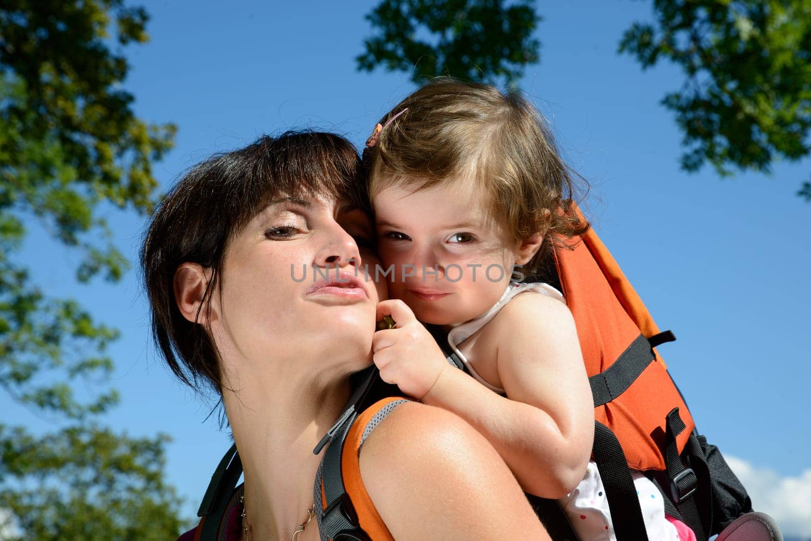 a little girl in a baby carrier walks with his mom