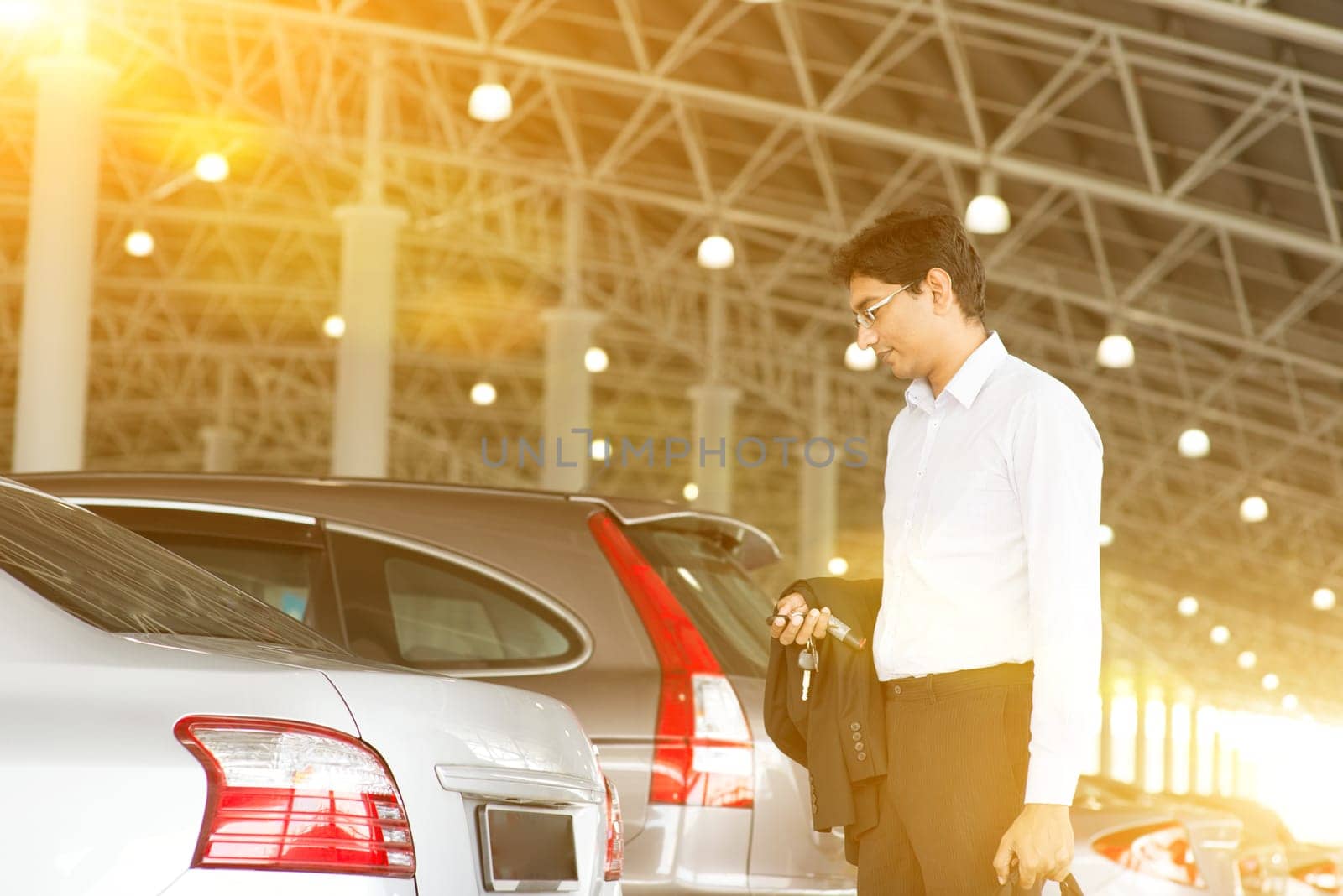 Indian business man at car park, holding car remote key.