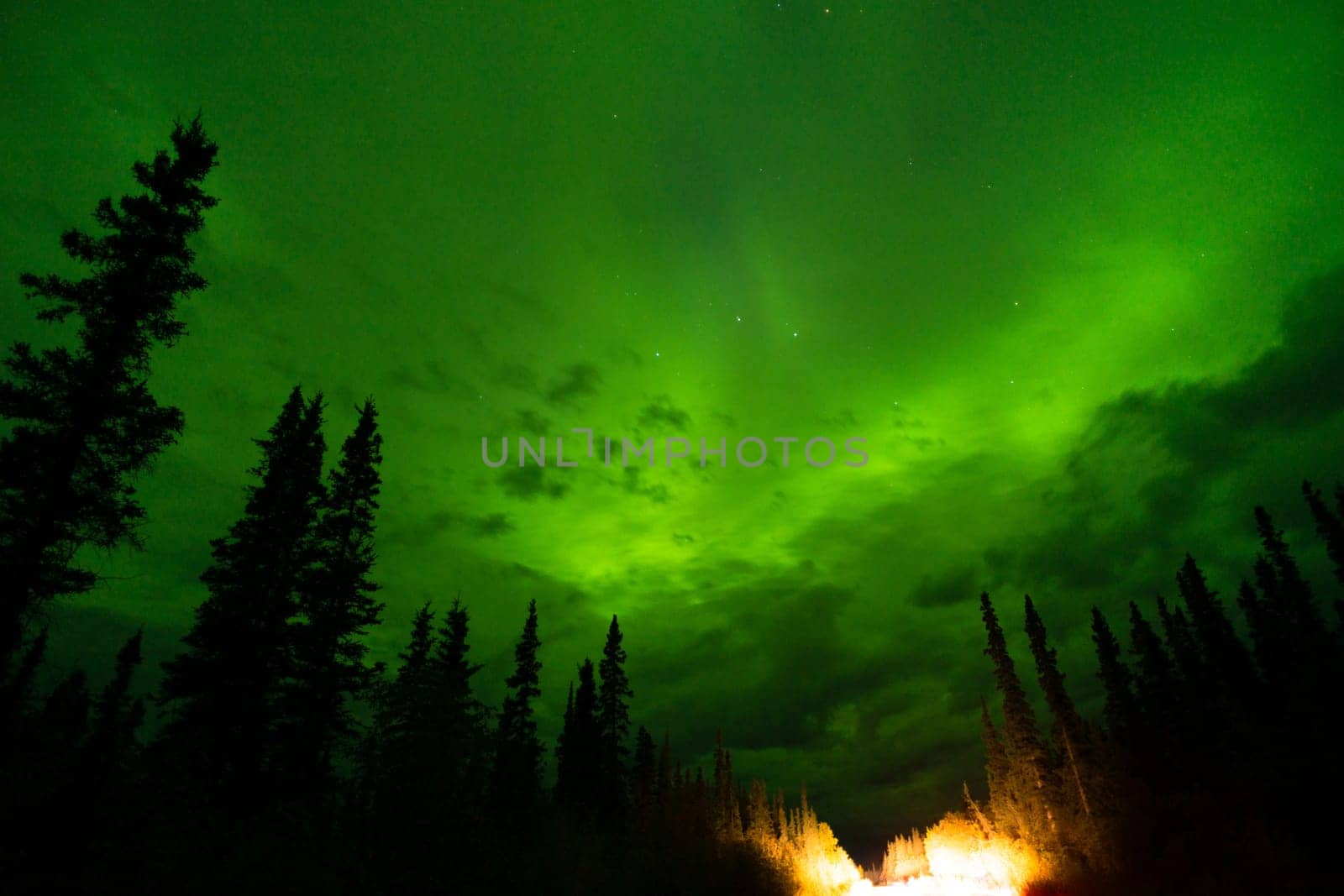 The Northern Lights emerge through the clouds in remote Alaska