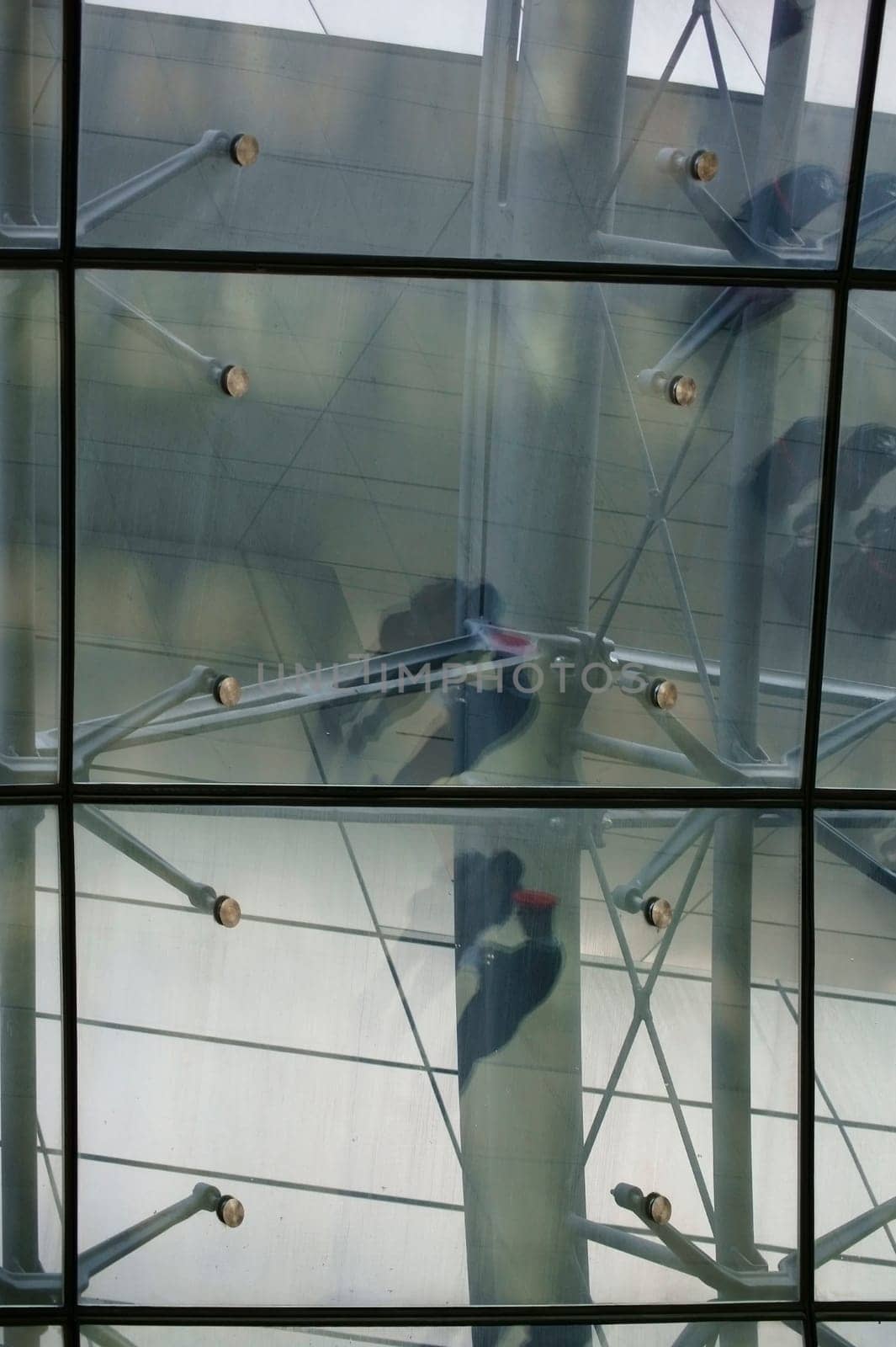 The abstract reflection of ticket inspectors,conductors and travellers in the roof construction of a railway station.