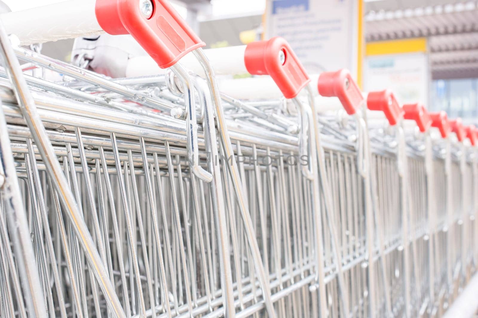 Rows of shopping carts on car park near entrance of supermarket