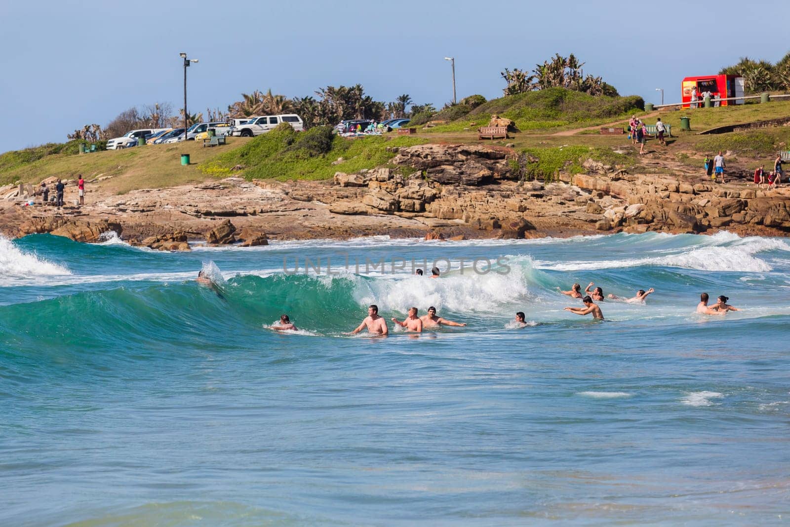 Ocean waves swimmers men women boys girls  in beach rocky landscape
