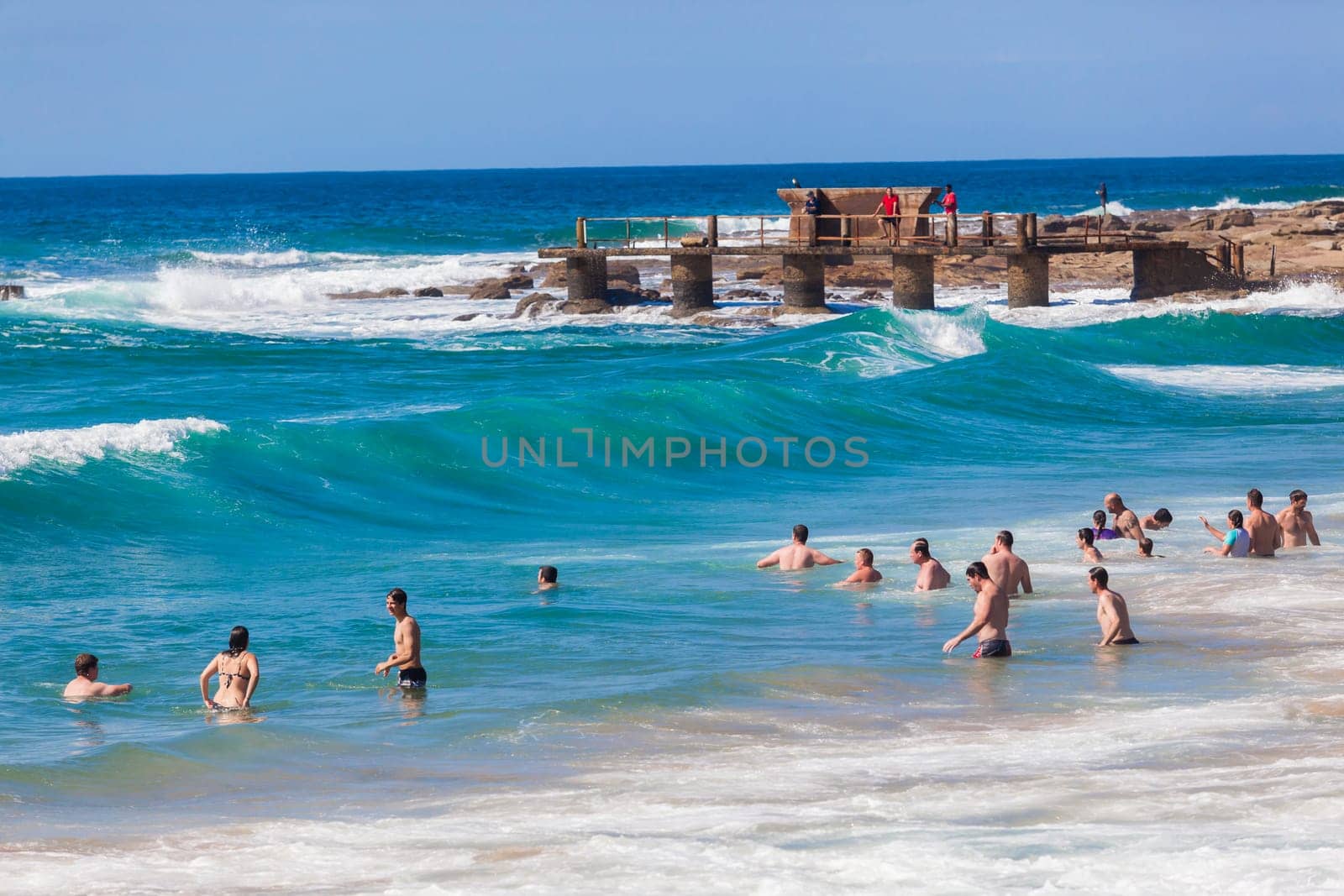 Ocean waves swimmers men women boys girls  in beach rocky landscape