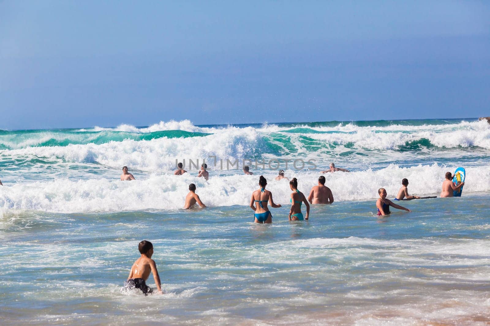 Ocean waves swimmers men women boys girls  in beach rocky landscape
