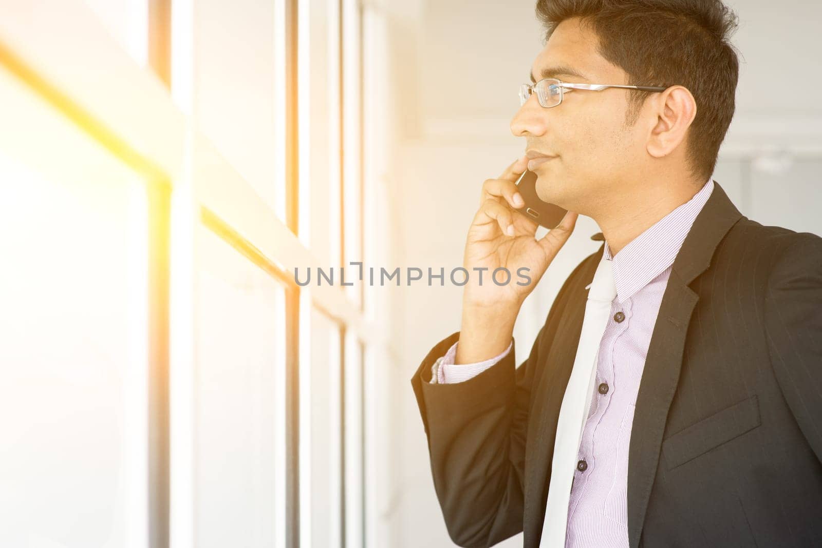 Indian estate agent checking on new office to let and calling on phone.