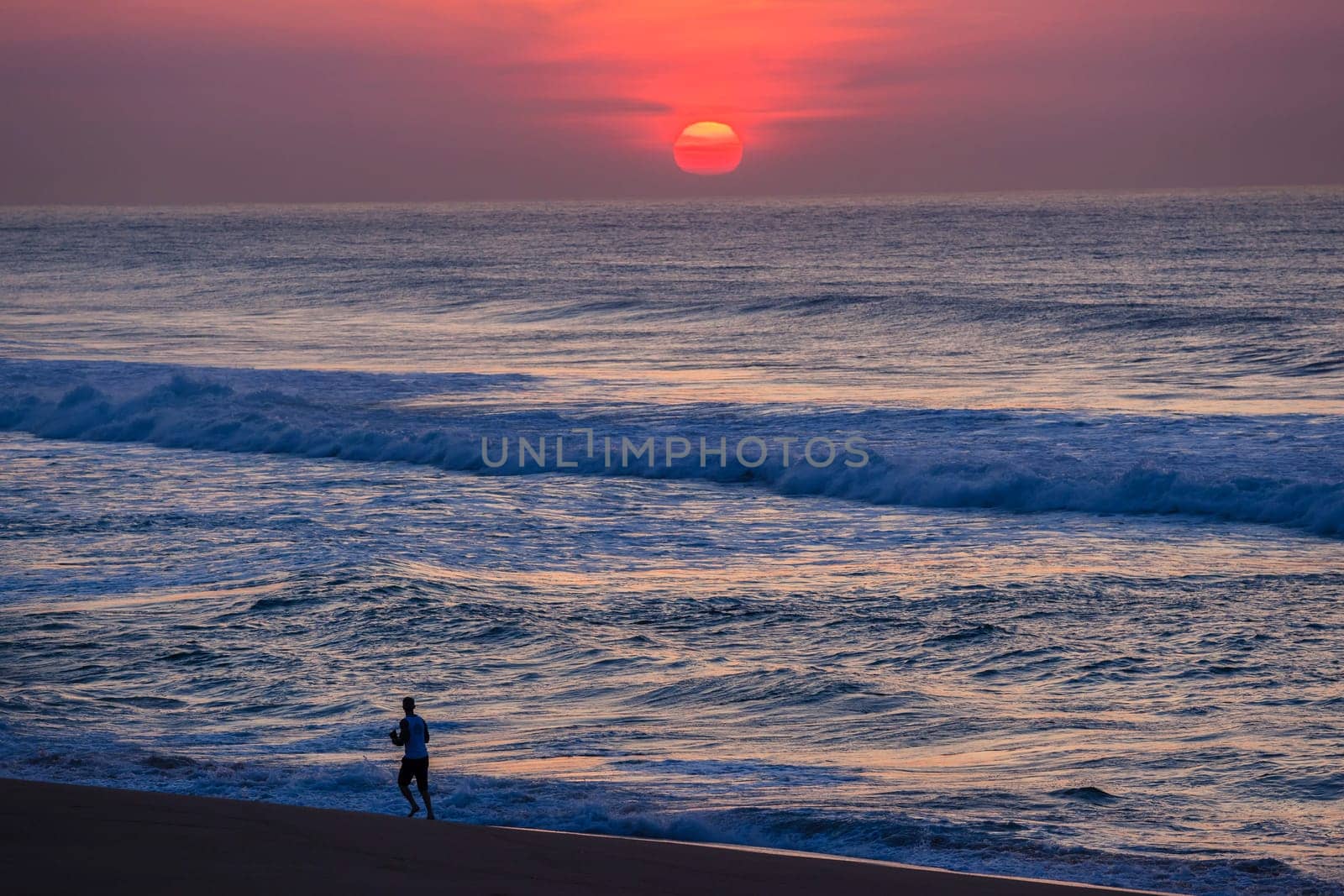 Ocean sunrise new day with runner along beach shoreline landscape