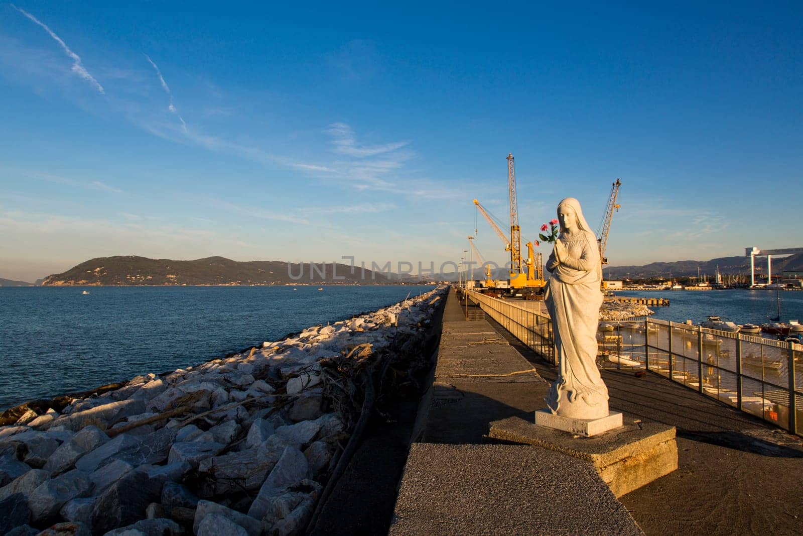 Close up view of the Virgin Mary patroness of seafarers and port with cranes in the background