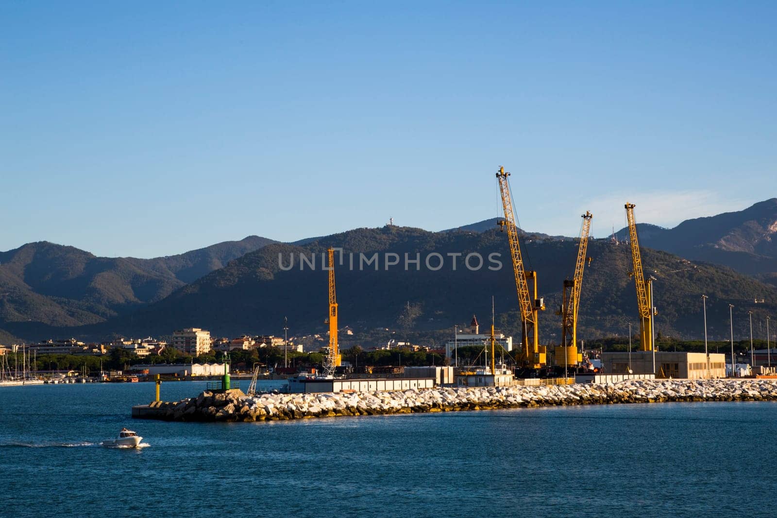 Panoramic view of a commercial port in a sunny morning with mountains in the background