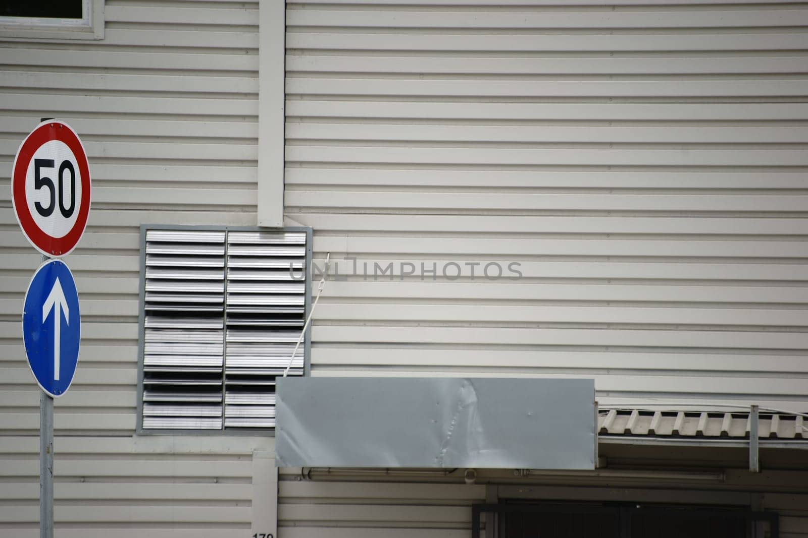 Roof boards and a stainless steel ventilation grille on a sheet metal wall of a public shopping building.