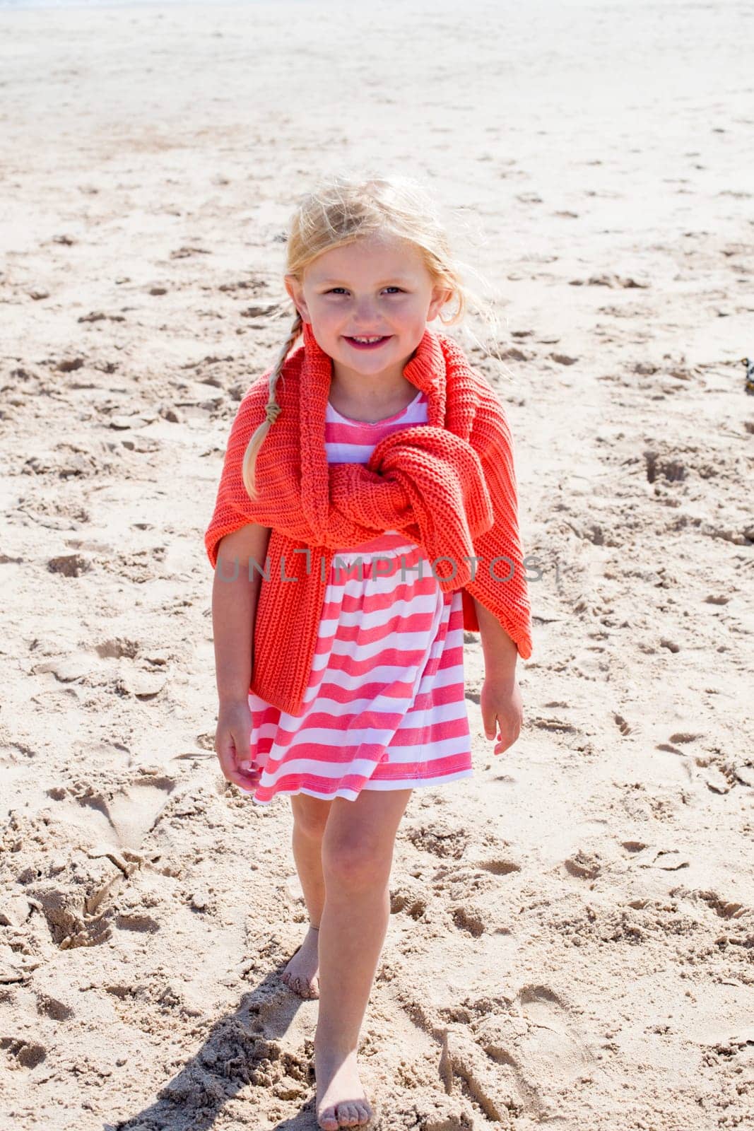 Little girl on the beach smiling at the camera.