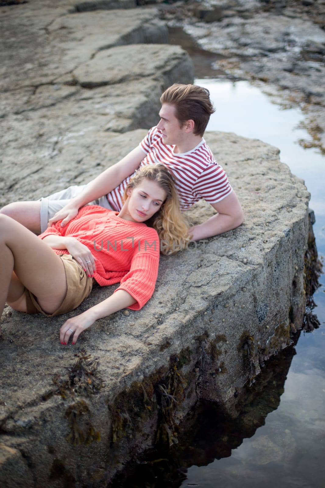 Beautiful couple lying on the rocks at the beach.