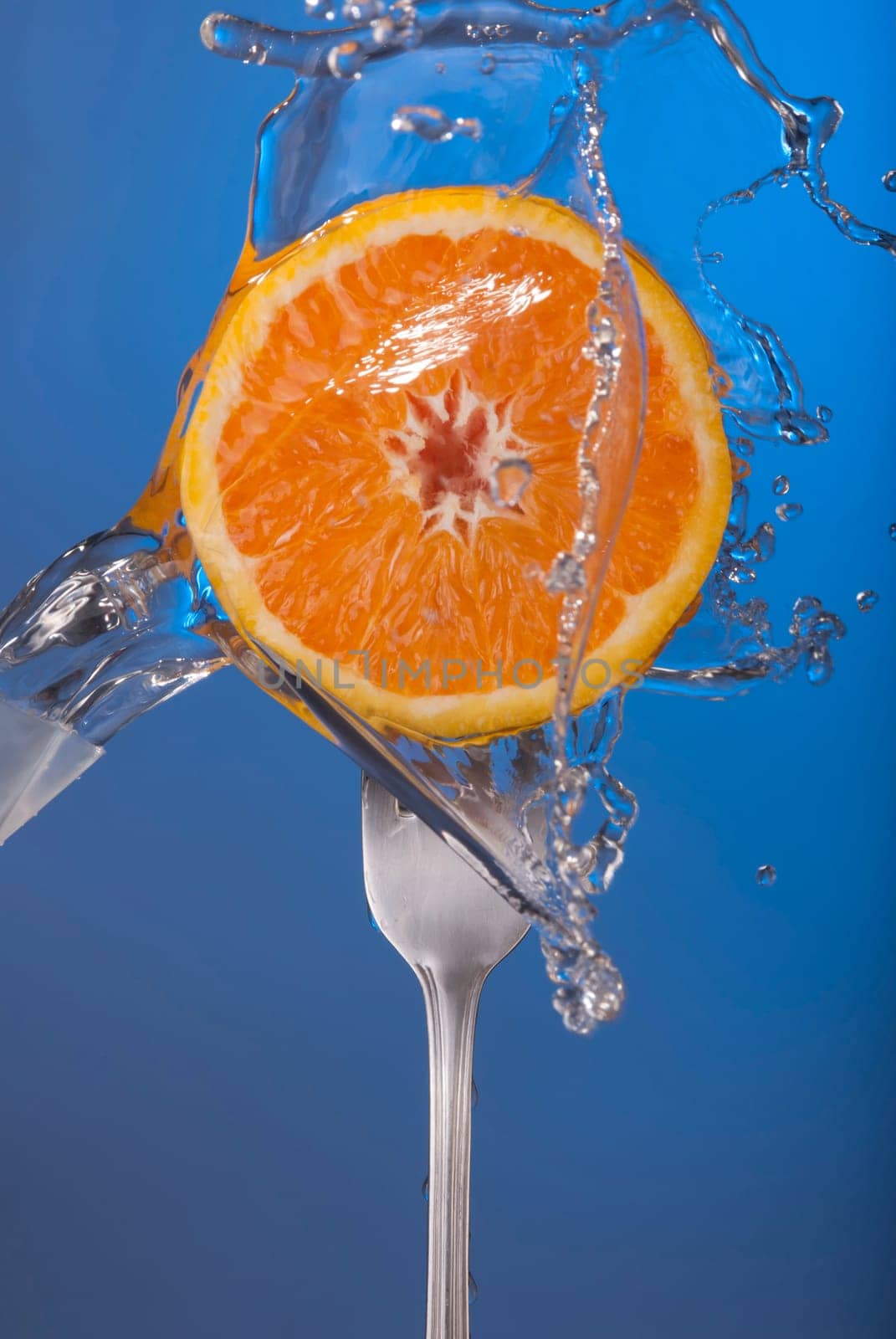 Orange fruit on fork with water splash and color background, concept photo. Ideal for healthy eating campaign or fitness poster.